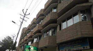 A multi-story building with a brick facade, multiple balconies, and a sign for 'KURUNI TOURS AND TRAVEL'.
