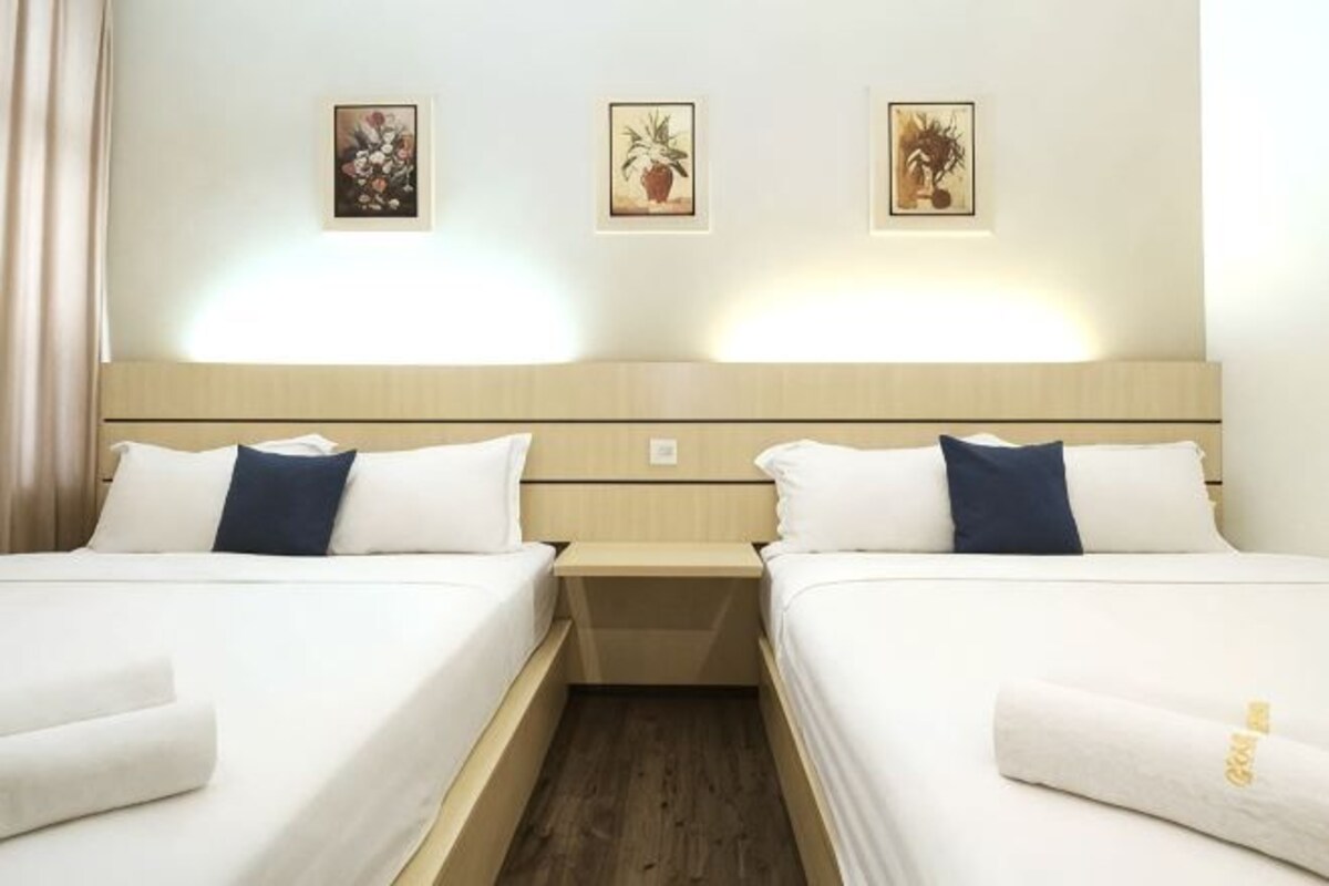 A hotel room with two beds, a wooden headboard, and wall-mounted artwork.