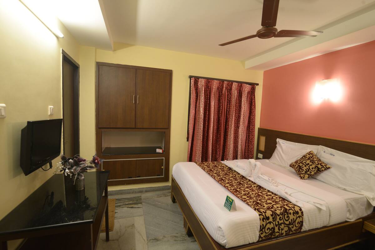 A hotel room with a bed, a television, a desk, and a wardrobe.