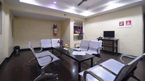 A conference room with a long table, several chairs, a ceiling fan, and a television on a stand. - Hotel Vijay (Madurai)