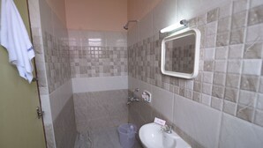 A bathroom with a sink, mirror, and shower. - Hotel Vijay (Madurai)