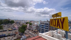 A hotel sign labeled "Vijay" in a bustling cityscape with multi-story buildings and a clear sky. - Hotel Vijay (Madurai)