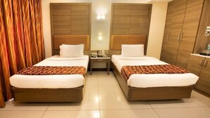 A hotel room with two beds, a nightstand, a mirror, and wooden wardrobes. - Clinton Park Inn (Nagapattinam)