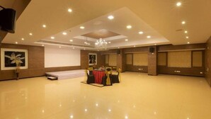 A spacious hall with a stage, a chandelier, and a projector screen. - Clinton Park Inn (Nagapattinam)