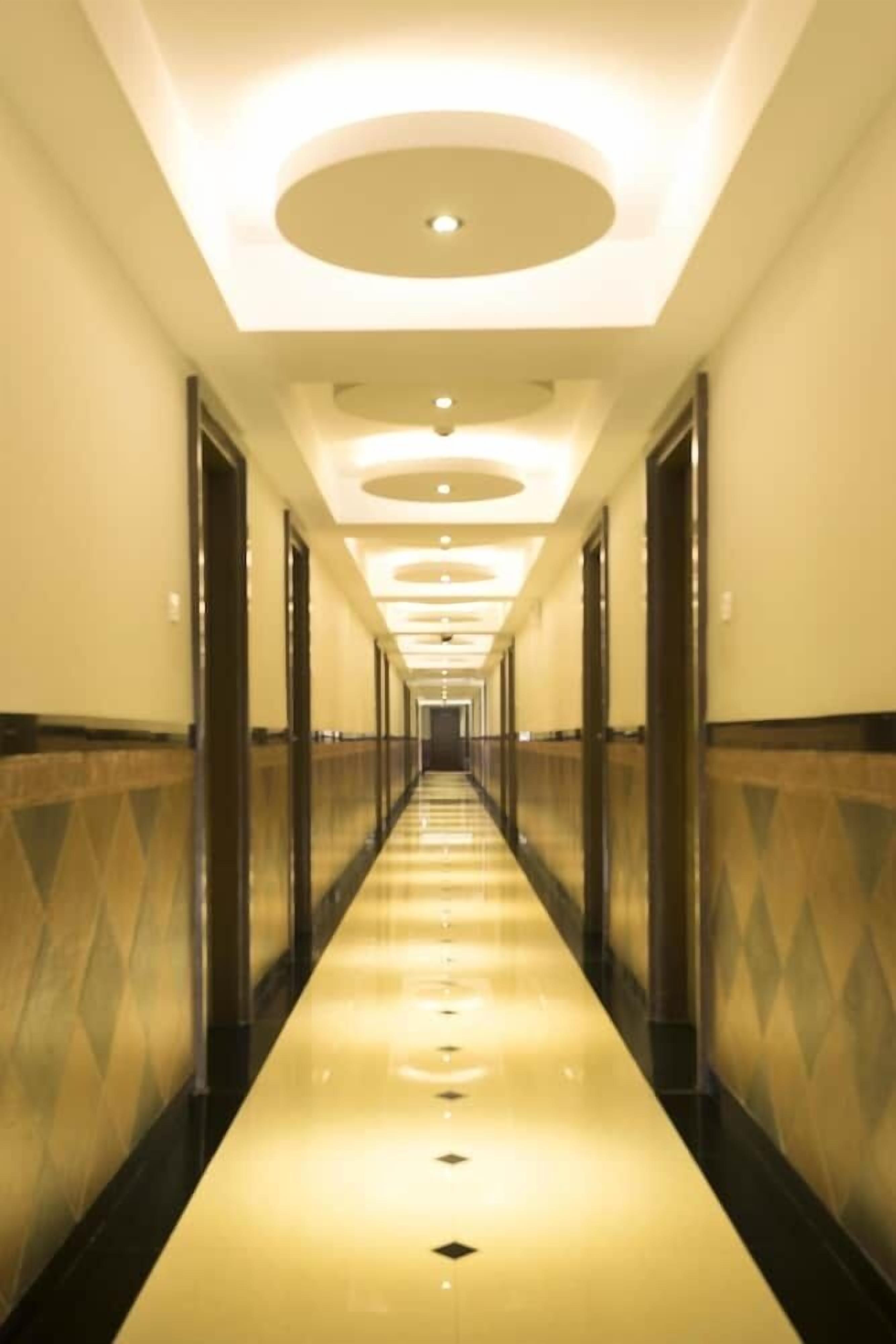A long, well-lit hallway with a reflective floor, leading to a door at the end.