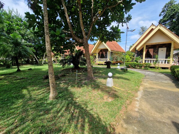 A bungalow with a tiled roof, surrounded by lush greenery and a well-maintained lawn.