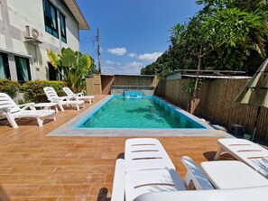 A swimming pool with lounge chairs, a wooden deck, and a building with large windows. - Rim Khao Jungle Resort Koh Lanta (Ko Lanta)