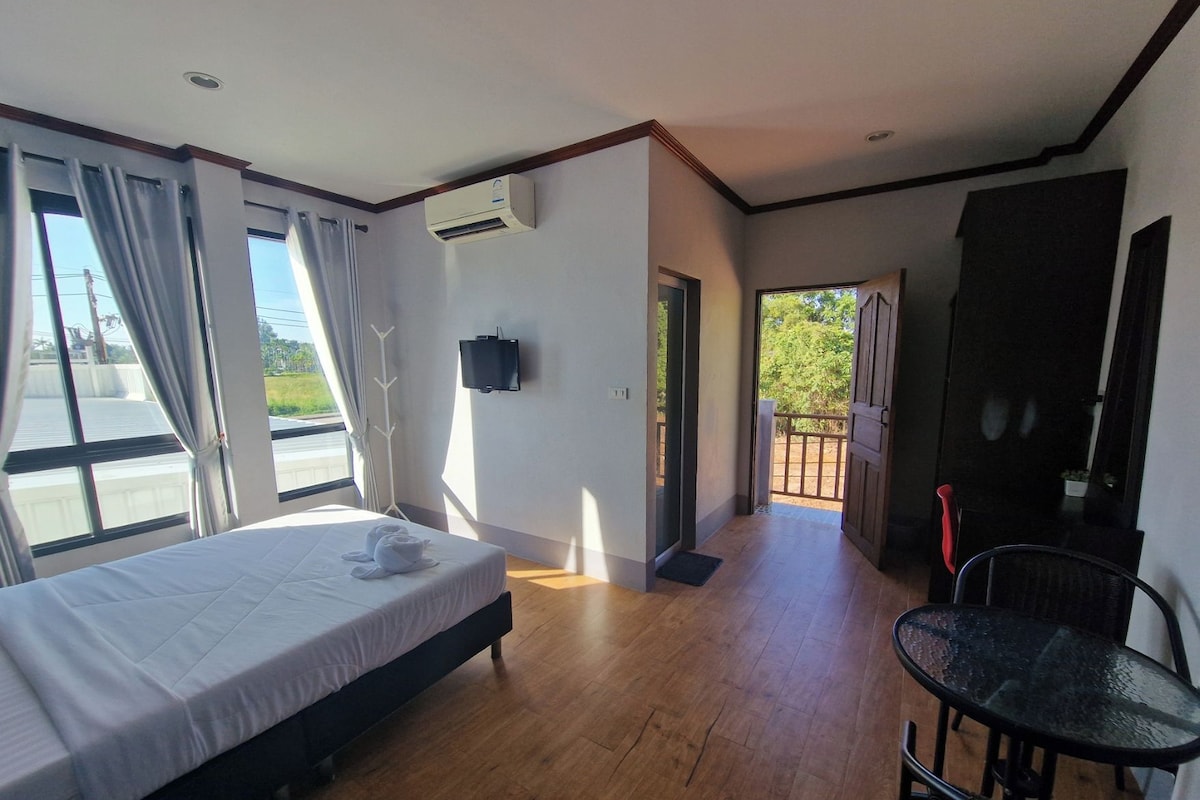 Habitació d'hotel amb llit, televisió, balcó i zona de menjador.
