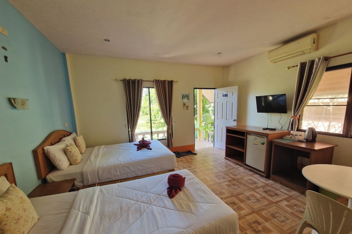 Habitació d'hotel amb dos llits, escriptori, televisió i petita cuina.
