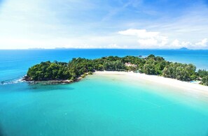 An aerial view of a tropical island with a beach, dense greenery, and clear turquoise waters. - Rim Khao Jungle Resort Koh Lanta (Ko Lanta)