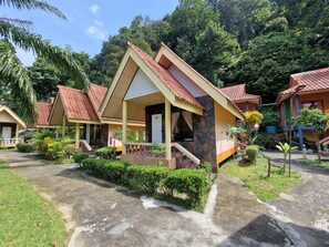 A row of traditional-style bungalows with tiled roofs, surrounded by lush greenery and a clear sky. - Rim Khao Jungle Resort Koh Lanta (Ko Lanta)
