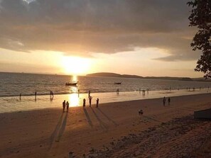 A beach with people, boats, and a sunset. - Sea Star House (Krabi)