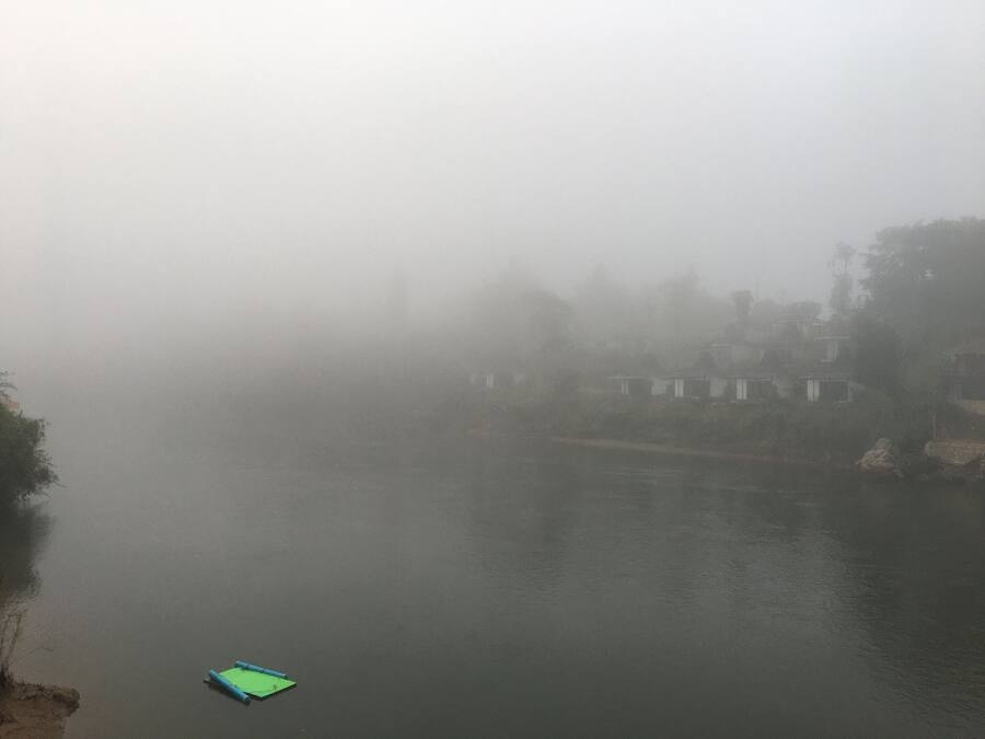 A foggy river scene with a small green boat.