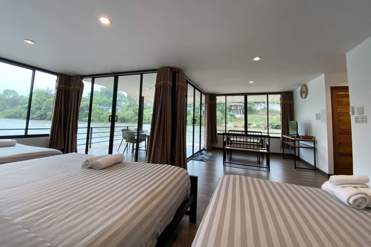 A modern hotel room with large windows, a balcony, and a view of a body of water.