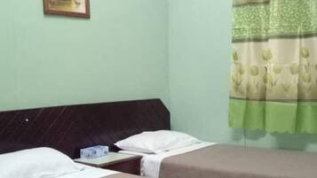 A hotel room with two beds, a ceiling fan, an air conditioning unit, a painting on the wall, and a curtain with a floral pattern.