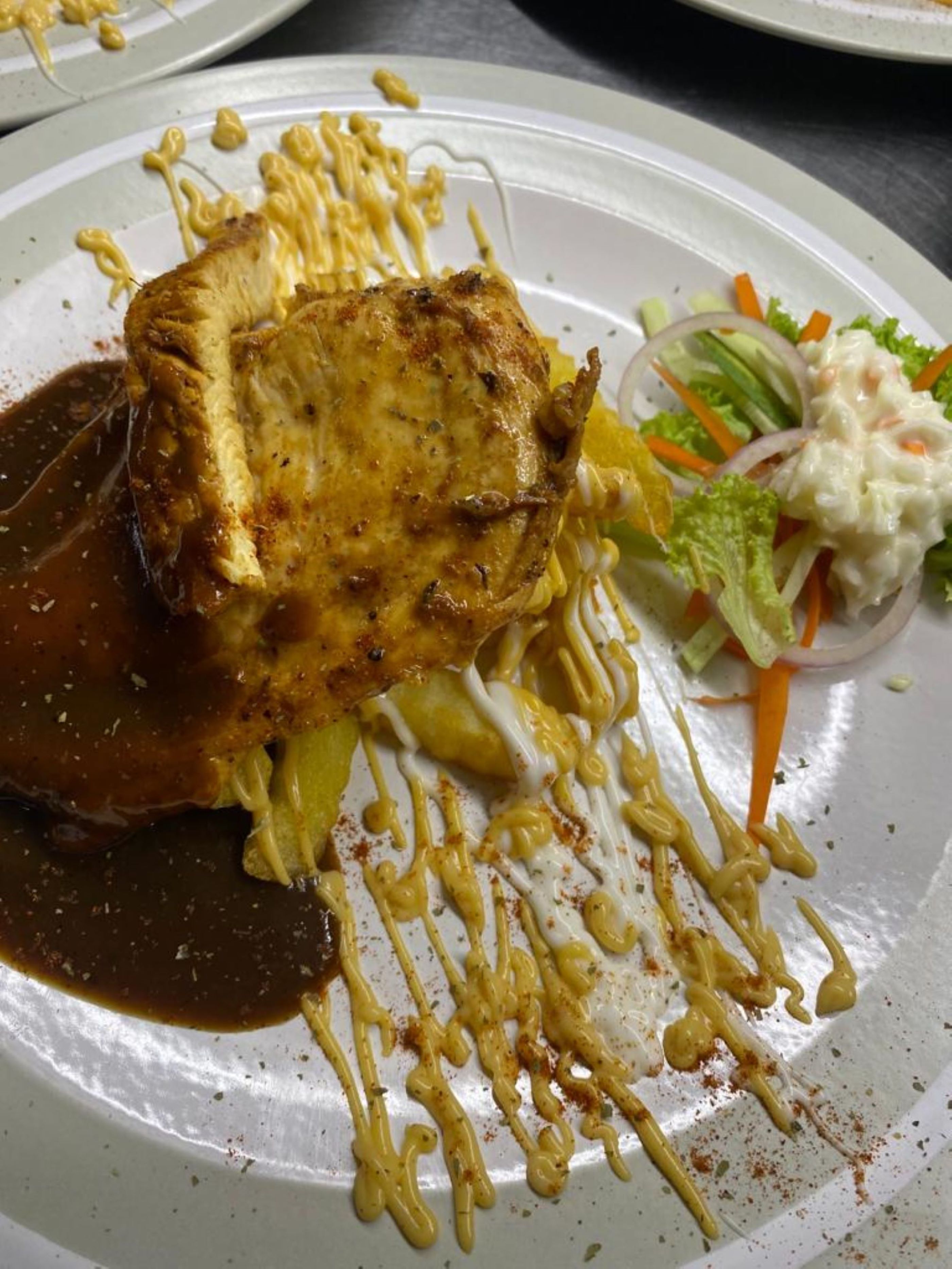 A plate of food with a piece of meat, vegetables, and a side salad.