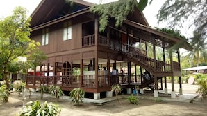 Uma casa de madeira de dois andares, com varanda e escadaria.