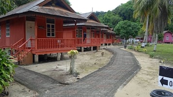 A traditional red wooden building with a tiled pathway leading to it.