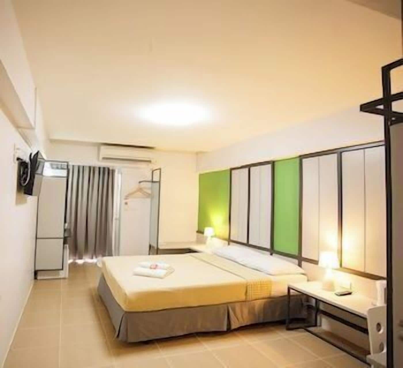 Une chambre d’hôtel avec un lit, une table de chevet et un mur d’accent de couleur verte.
