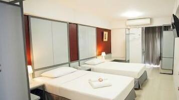 A hotel room with two beds, a wardrobe, a mirror, a bedside table, and a lamp.