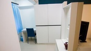 A compact room with a desk, chair, and a wardrobe. - Regent Ngamwongwan (Nonthaburi)