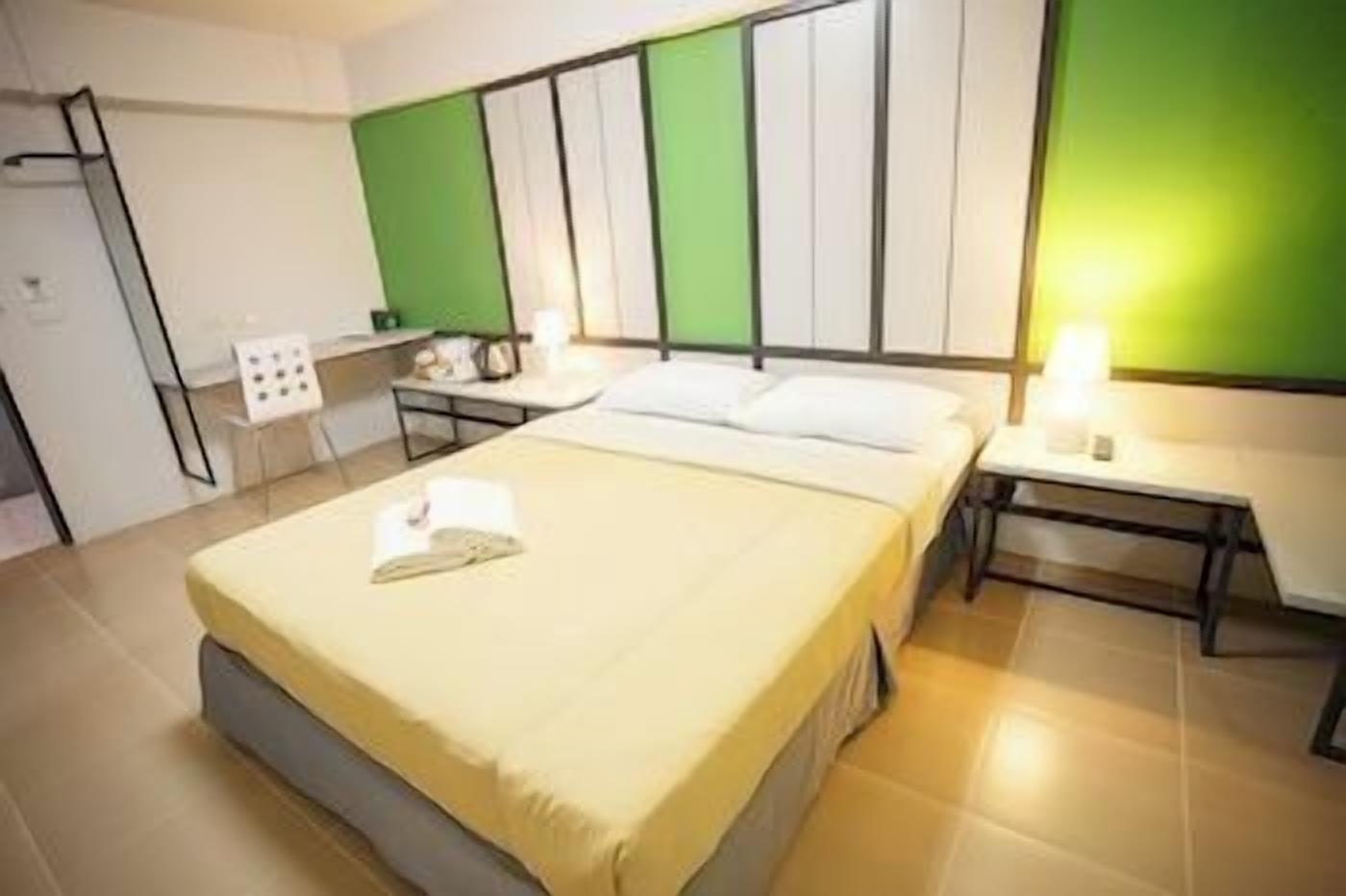 A hotel room with a bed, bedside tables, a desk, and a chair.
