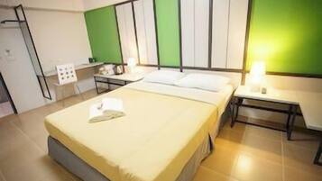 A hotel room with a bed, bedside tables, a desk, and a chair.