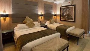 A modern hotel room with two beds, a large painting, and a built-in air conditioning unit. - Shari-La Island Resort (Teluk Aur)