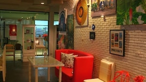 A modern interior with a red sofa, a glass table, and a brick wall adorned with artwork. - Khaolak Palm Hill Resort (Takua Pa)