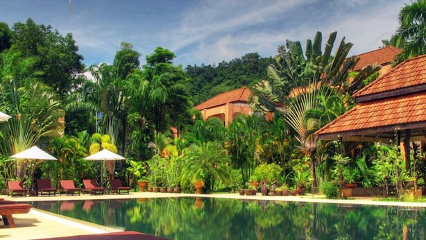 A poolside area with lounge chairs and umbrellas, surrounded by lush tropical vegetation. - Khaolak Palm Hill Resort (Takua Pa)