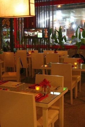 A restaurant with tables set for dining, chairs, and a lamp.