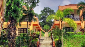 A building with a staircase leading to a balcony, surrounded by lush greenery and potted plants. - Khaolak Palm Hill Resort (Takua Pa)