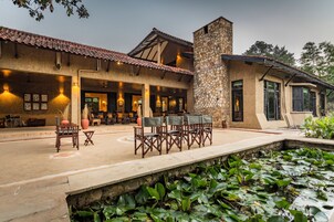 Un edificio con fachada de piedra, techo de tejas y un patio con mobiliario exterior.