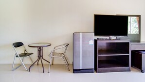 Ein gemütlicher Raum mit Flachbildfernseher, Kühlschrank, kleinem Tisch und zwei Stühlen.