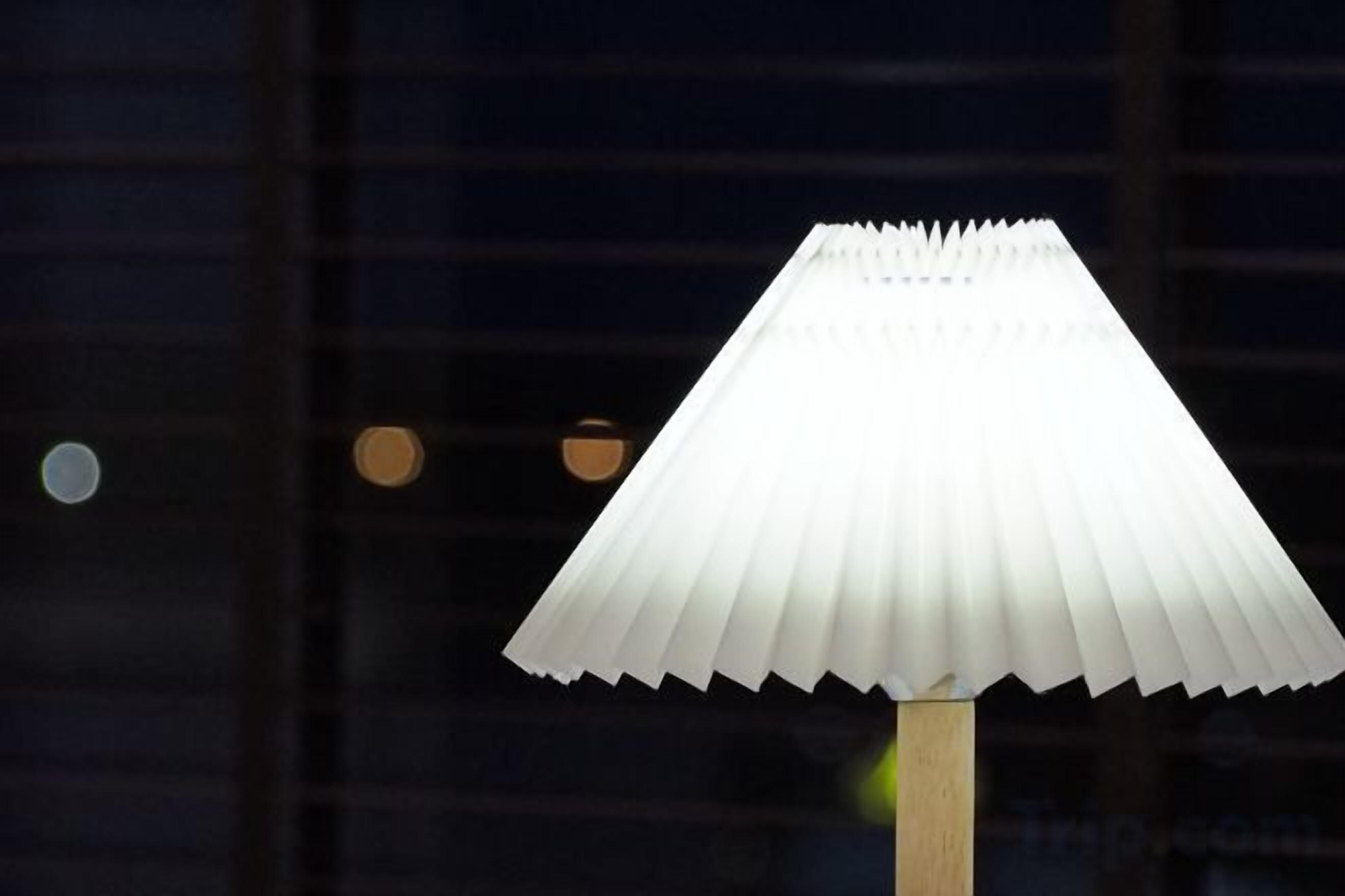 A white, pleated lamp on a wooden stand.