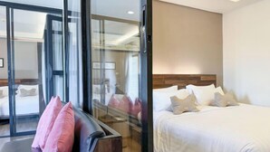 A hotel room with a bed, a sofa, and a sliding glass door leading to a balcony. - Amphawa Nanon Hotel (Amphawa)