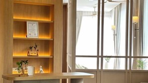 A reception desk with a wooden finish, a wall-mounted certificate, and a potted plant. - Amphawa Nanon Hotel (Amphawa)