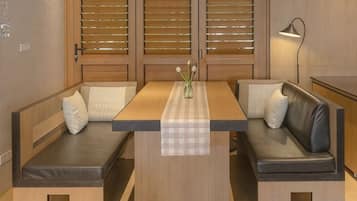A room with a wooden table, two cushioned benches, and a lamp.