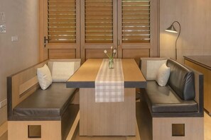 A room with a wooden table, two cushioned benches, and a lamp. - Amphawa Nanon Hotel (Amphawa)