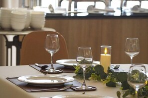 A dining table set with plates, glasses, and a candle. - Amphawa Nanon Hotel (Amphawa)