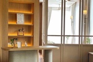 Una recepción con detalles de madera, un certificado enmarcado y una planta pequeña. Hay una ventana con cortinas y vista al exterior.