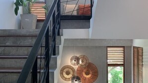 A staircase with a modern design, a potted plant, and a wall-mounted light fixture. - Amphawa Nanon Hotel (Amphawa)