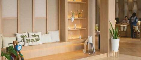 Un moderno vestíbulo de hotel con mostrador de recepción, zona de estar y una planta.