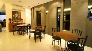 A modern dining area with a wooden table and chairs, a small bar area, and a framed picture on the wall. - At One (Bangkok)