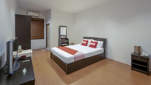 Habitació d'hotel amb un llit, una taula de treball amb un ordinador, un televisor i una taula petita amb un telèfon.
