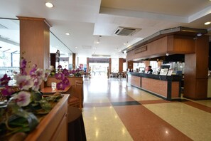 Un hall d’hôtel comprenant un comptoir d’accueil, un espace salon et une vue sur l’entrée.