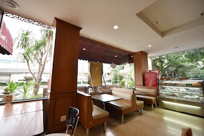 A restaurant with indoor seating, a counter, and a display case with food items. - Bangkok City Suite (Bangkok)