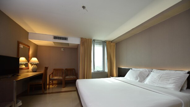 A hotel room with a bed, desk, chair, and a window with curtains. - Bangkok City Suite (Bangkok)