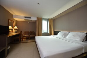 A hotel room with a bed, desk, chair, and a window with curtains. - Bangkok City Suite (Bangkok)