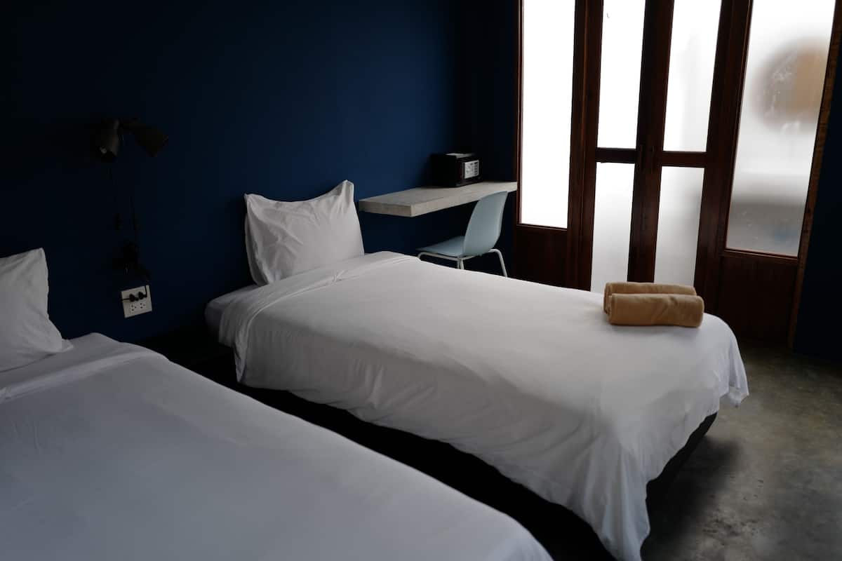 A hotel room with two beds, a desk, and a chair.